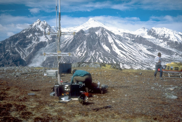 Seismometers such as this one installed near Mount 
Spurr volcano (on skyline in background) provide the Alaska 
Volcano Observatory with a continuous, radio-telemetered 
record of volcanic earthquakes. These data are used to 
monitor the state of activity at the volcano and are 
critical to the ability of the Observatory to issue timely 
warnings of eruptions. View is to the north. Photograph by 
C. Neal , U.S. Geological Survey, June 3, 1993.