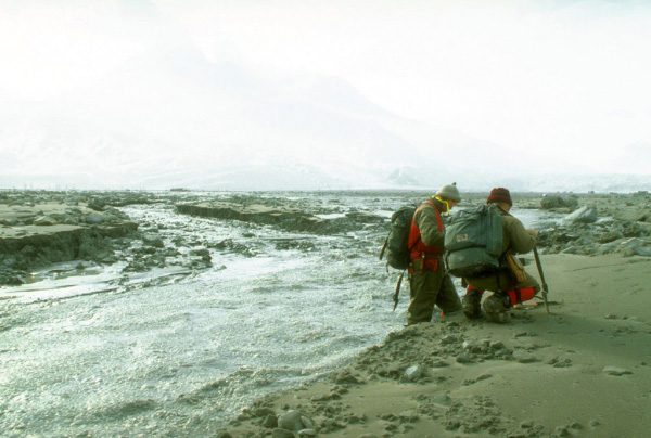 Geologists Jon Major and Ed Wolfe view an unusual flowing mixture of water and 
ice in the upper Drift River. The flow was produced by a 
sudden release of impounded water from the upper reaches of 
the Drift River canyon which drains the summit crater of 
Redoubt Volcano. Photograph by G. McGimsey, U.S. Geological 
Survey, March 15, 1990.