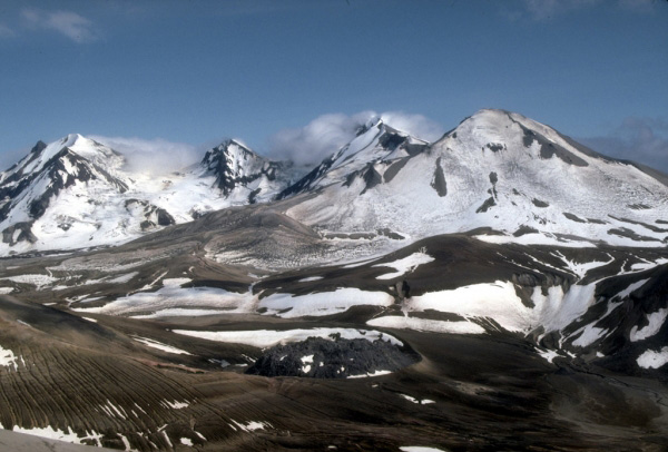 The multiple peaks of Trident Volcano as viewed from the top of Baked Mountain in the
Valley of Ten Thousand Smokes, Alaska.  Trident Volcano is composed of a cluster of andesite and dacite cones and is the only Katmai group volcano other than Katmai and Novarupta to have had historical activity. The Novarupta lava dome is visible at bottom, center. Photograph by R. McGimsey, U.S. Geological Survey, July 12, 1990.