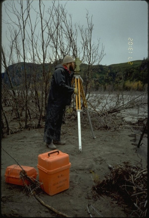 Hydrologist uses a theodolite to survey channel morphology along the Drift River which drains Redoubt Volcano.  This information is used to calculate water flow and to track the changing geometry of channels which can affect downstream hazards.  Volcanic activity in Alaska where many volcanoes are covered with snow and ice year-round poses an especially great hydrologic risk along radiating drainages due to the melting by hot volcanic debris.
