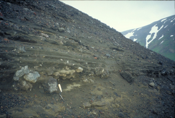 Surge deposits exposed on Sugarloaf, a flank vent of Makushin Volcano.  These deposits may be indicative of the explosive interaction of lava with groundwater.  Trowel is for scale.  View is from the northeast.