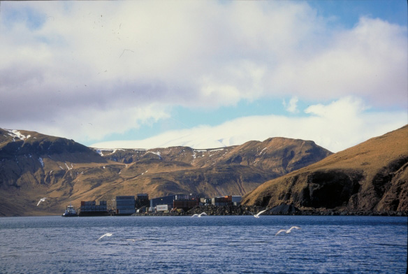 Trident seafood processing plant at Akutan Harbor.  Akutan Volcano obscured by clouds in the center of the photo.