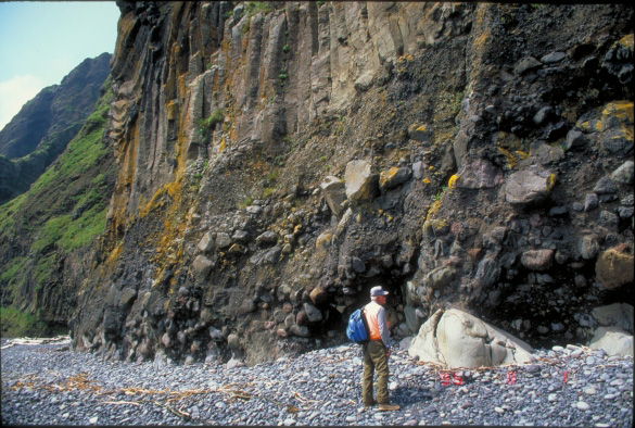 Don Richter examines subaqueous debris flow deposits and overlying columnar-jointed lava flow at Cape Morgan, Akutan Island.