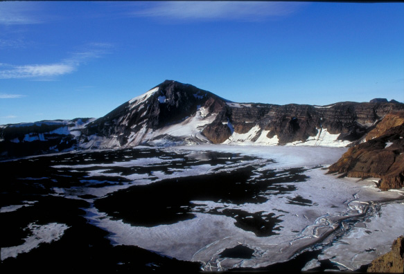 West half of the Akutan caldera floor, containing a partially ice-covered lake.  The high point on the rim is Akutan Peak (1303m).