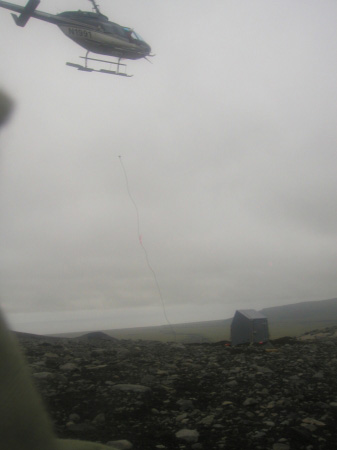 Creating station OKSO (Okmok South).  With the hut in place, the helicopter drops the hoist and heads off in search of the next load.