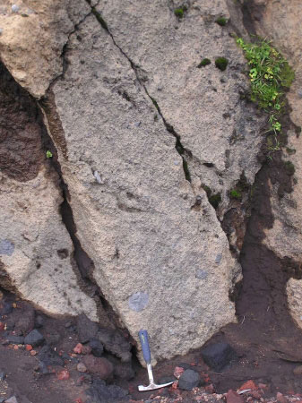 A zoomed in photo of an undated pyroclastic deposit near the southern edge of the newly formed volcaniclastic debris flow fan deposit from the 2001 eruption. Geologic hammer for scale. Some larger clasts of are visible within the deposit. There was some strength to the deposit suggesting some possible welding of the pyroclastic material.