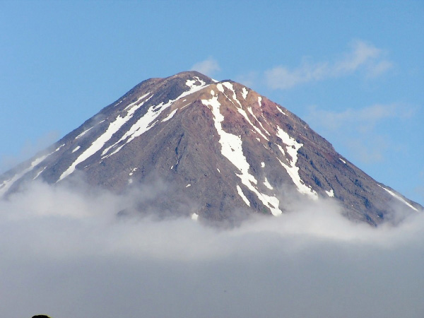Photo of the exposed portion fo the southern flank and summit region of Mt. Carlisle as observed from the volcaniclastic debris flow fan deposit created from the 2001 Mt. Cleveland eruption. The photo was enhanced for better contrast to decrease the amount of haze. What appears to be steam from the summit is actually fractus clouds behind the volcano.