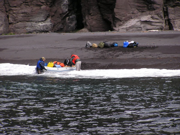 Photo of skiff operations to return the field gear from the beach north of the volcaniclastic debris flow fan deposit to the Augusta D to end the 2003 field campaign on Mt. Cleveland. Scott Kerr (assistant on the Augusta D - in the water on the left) and Mike Brown (formerly of Kansas State University - on the right) prepare to float the skiff to return to the Augusta D.