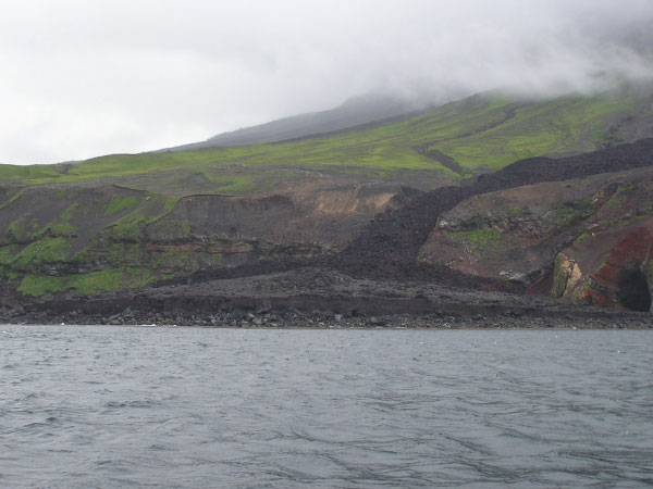 Photo of the volcaniclastic debris flow fan deposit taken from the Augusta D located just to the west-southwest of the fan deposit. The secondary fork of the northern fork of the 2001 lava flow is observed on the west flank. The steep erosional edge of the fan deposit has been formed by the wave action.