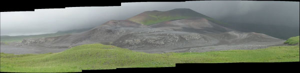 Panoramic photo of the main cinder cones located on the eastern part of the central isthmus of Chuginadak Island as viewed from the western side of the isthmus (eastern flank of Mt. Cleveland) on the north side of another cinder cone. An undated lava flow makes up a cliff on the northern part (left side of the photo) of the one cinder cone.