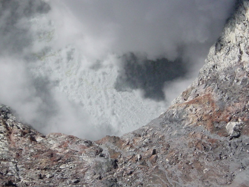 Close-up view down into the roiling pool that occupies the summit crater of Korovin volcano.  Rivlets of ash can be seen that have run back down into the bare rock margin around the pool.