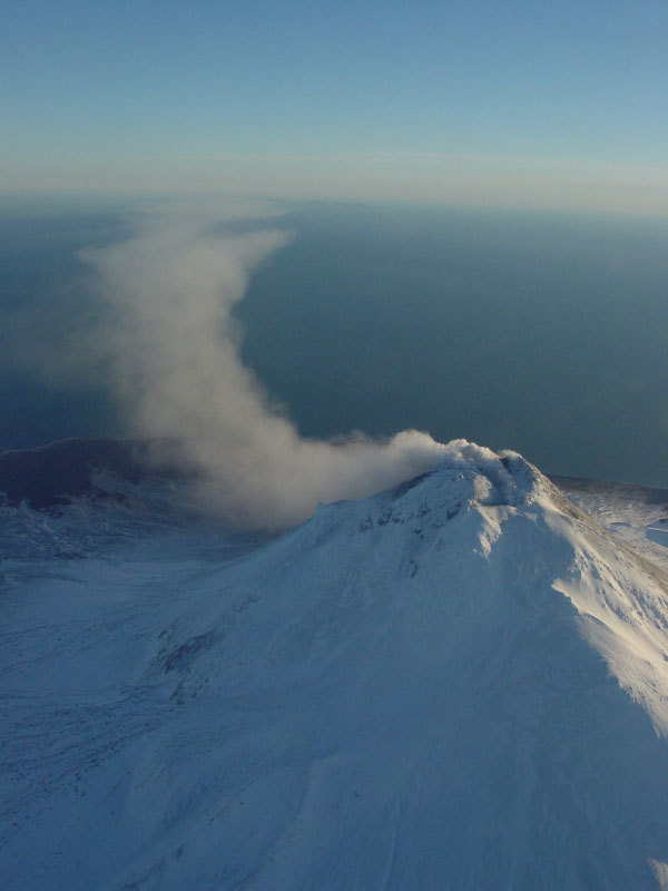 Steam issuing from multiple fumaroles on the summit, and upper southeast flank; steam and gas plume trailing 75 km downwind to southeast