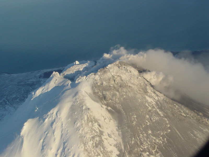 Steam issuing from multiple fumaroles on the summit and upper southeast flank of Augustine volcano; steam and gas plume trailing 75 km downwind to southeast