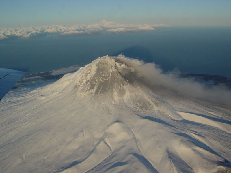 Steam issuing from multiple fumaroles on the summit, and upper southeast flank; steam and gas plume trailing 75 km downwind to southeast