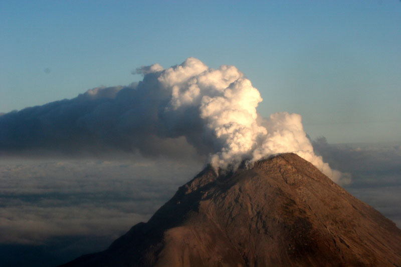 Augustine Volcano. Image taken during observation flight on 1/18/06. View is from the northwest. The steam plume travels east at an approximate altitude of 8500 ft. The vigorous plume travels for many miles above the cloud deck at approximately 4000 ft.