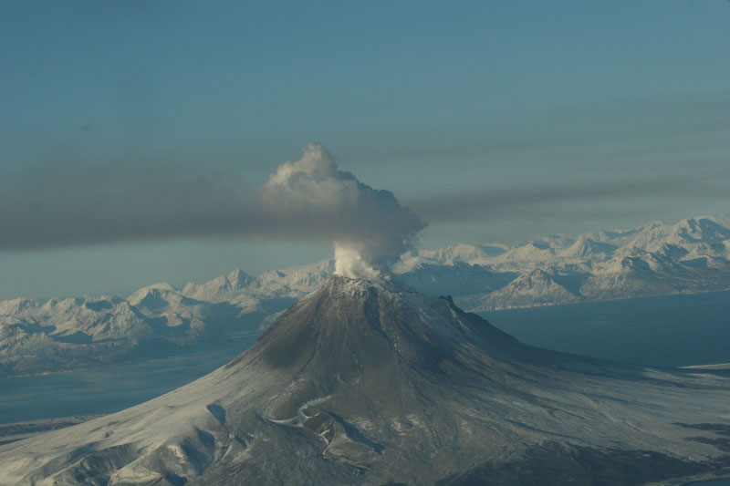 Augustine Volcano on January 24, 2006.  Steam and gas plume is drifting to the S SE.  The pinkish/brown haze in the foreground is smog from volcanic gases in the plume.  This photo was taken during a gas flight where a fixed-wing plane flies through the diffuse plume measuring gases.