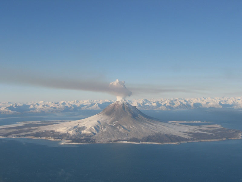 Augustine Volcano on January 24, 2006.  Steam and gas plume is drifting to the S SE.  The pinkish/brown haze is smog from volcanic gases in the plume.  This photo was taken during a gas flight where a fixed-wing plane flies through the diffuse plume measuring gases.