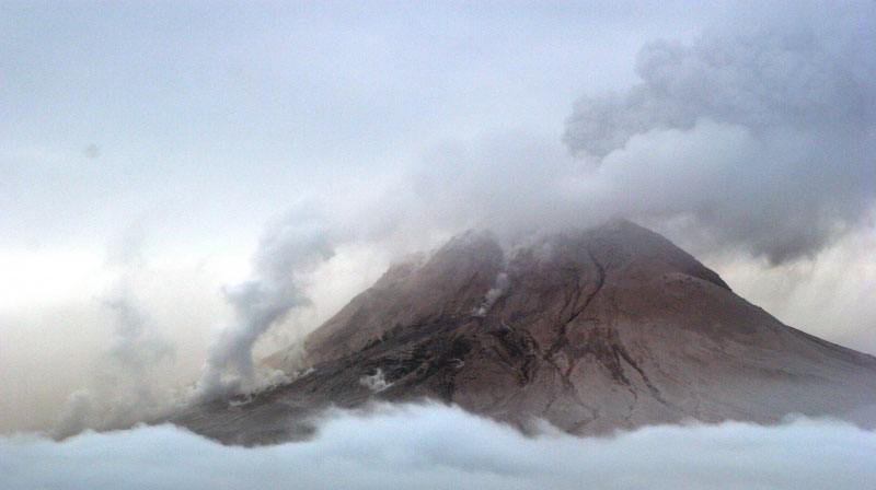 Augustine Volcano on 1/29/06 observation overflight.  Photo of west and north flanks of the volcano. Steam and gas on the mid and lower flanks is from a recent pyroclastic flow deposit on the north flank (probably emplaced within an hour of the photo being shot).  The main ash and gas plume is drifting to the S SW.
