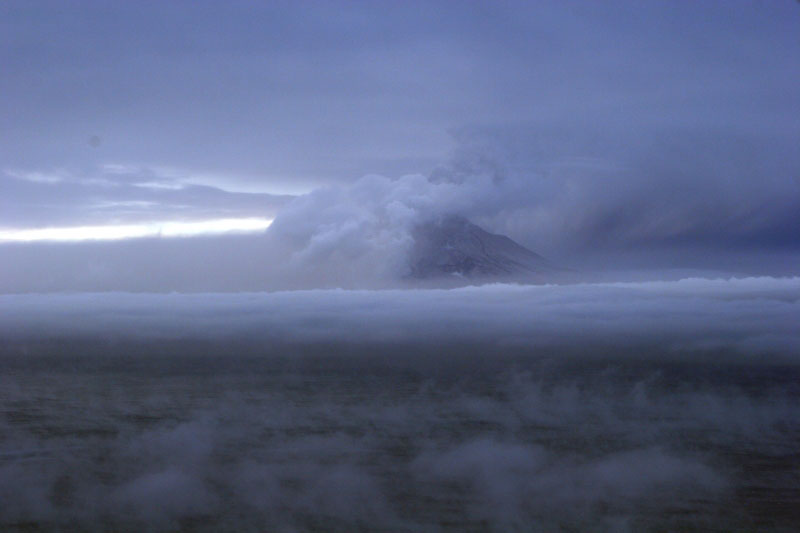 Augustine Volcano on 1/29/06 observation overflight.  Photo from the north with view of west flank of the volcano. White steam and gas on north flank is from a recent pyroclastic flow deposit on the north flank (probably emplaced within an hour of the photo being shot).  The main ash and gas plume is drifting to the S SW.
