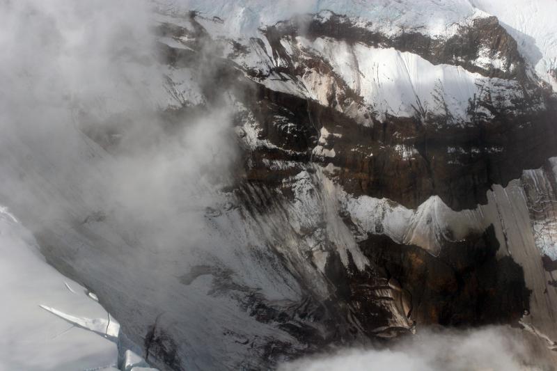 Headwall of Fourpeaked Glacier NE of the summit of Fourpeaked volcano.  Waterfalls were issuing from beneath the ice at the top of the headwall at an elevation of 5,000 feet (1,900 feet below the summit).  A convective vapor plume was rising above the cloud deck between the summit (obscured by clouds) and the headwall region.