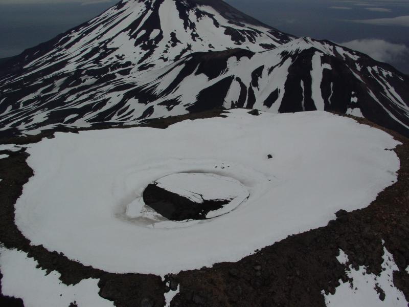 Summit crater of Kluichef.  Crater supports a small body of water that was only partially iced-over on this day.  Korovin in far distance, and Konia in middle ground.