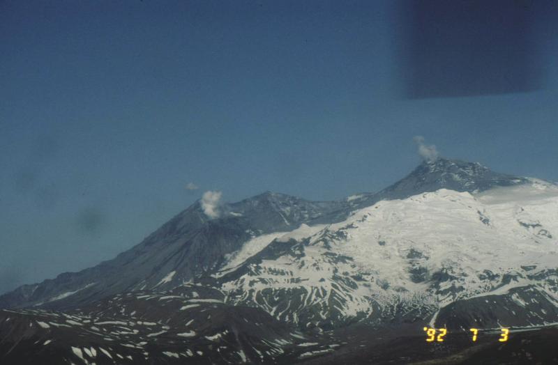 Mount Spurr Volcano six days after the June 27, 1992 eruption of its Crater Peak vent (darkened, steaming cone at lower left).  The tephra fall and ash cloud traveled almost due north from Crater Peak, darkening the glacier-covered true summit of Mount Spurr (steaming peak at right) and dusting climbing routes on Denali in the Alaska Range.  Crater Peak erupted two more times in the summer of 1992. Spurr is the closest volcano to Alaska&#039;s largest city of Anchorage - only 80 miles east of the volcano.