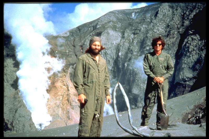 John Paskievitch and John Power at the remains of a seismic station on the East Rim of Crater Peak, Mount Spurr Volcano, the nearest active volcano to Anchorage.  The late June 1992 eruption from Crater Peak (right behind these two fellows) blasted 44 million cubic meters of ash, blocks, and gas into the atmosphere.  The combined mechanical and thermal damage to AVO&rsquo;s seismometer perched on the rim of Crater Peak destroyed the equipment, leaving only twisted galvanized steep pipe, melted coaxial cable, and corrugated metal.  Thanks to this and other seismic stations on the volcano prior to the eruption, however, AVO was able to issue early warning of the explosion.