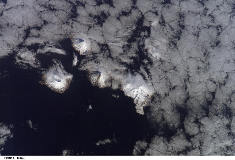 The Islands of the Four Mountains region, as viewed from space.  The western-most volcano is Herbert, followed by Carlisle.  Slightly to the east, the ash-streaked flank of Cleveland on Chuginadak Island is visible.  Chuginadak's other volcano, Tana is also visible to the east of Cleveland.  Kagamil lies further to the northeast, and is mostly obscured by clouds.  
This photograph is mission ISS014, Roll E, Frame 16045 from Image Science and Analysis Laboratory, NASA-Johnson Space Center. "The Gateway to Astronaut Photography of Earth." and is available at http://eol.jsc.nasa.gov/scripts/sseop/photo.pl?mission=ISS014&roll=E&frame=16045
