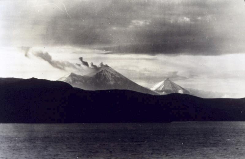 View of Mt. Pavlof steaming.  Small peak behind and to the left of Pavlof is Little Pavlof; peak to the right (east) is Pavlof Sister. Photograph taken by Captain Harry D. Reed, Coast and Geodetic Survey. Photograph from National Oceanic and Atmospheric Administration/Department of Commerce Photo Library, America's Coastlines Collection.