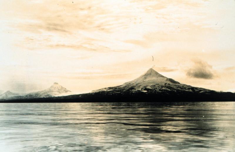 View of Shishaldin steaming.  Peaks behind and to the left (east) of Shishaldin are Isanotski and Roundtop. Photograph taken by Captain Harry D. Reed, Coast and Geodetic Survey. Photograph from National Oceanic and Atmospheric Administration/Department of Commerce Photo Library, America's Coastlines Collection.
