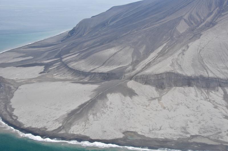 Southwest flank of Kasatochi island. Cliff like feature that rims the island is the former shoreline.The grey material covering the flanks of the island are pyroclastic surge and fall deposits.