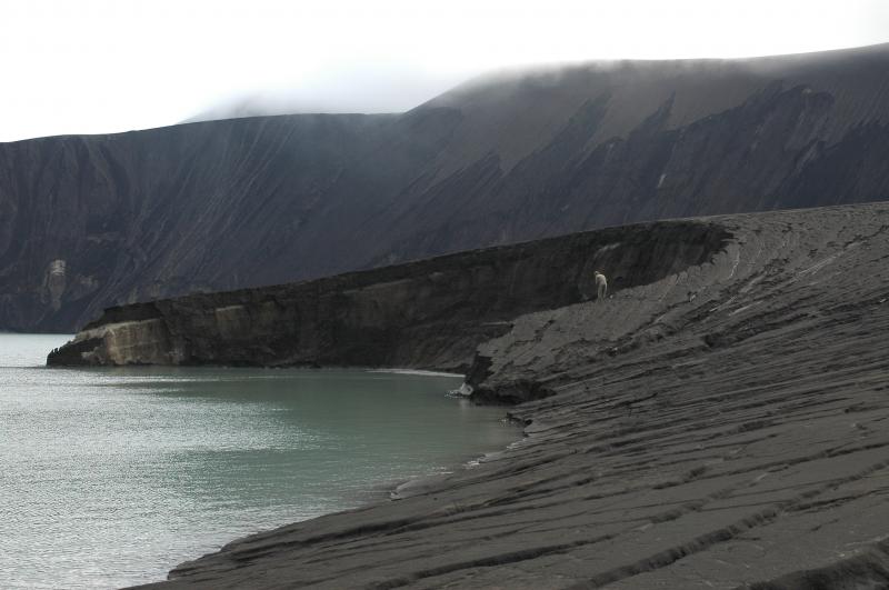 West shoreline of 'old' Cone D lake, new tephra cone in the distance at right, and the steep modfied wall of Cone D in the distance at left.  Foggy shrouded summit of Cone D at top.  Max is watching Jessica who is over the edge examining the section and trying to keep from sloughing into the lake.  The scalloped reentrant here could be an explosion crater rim.