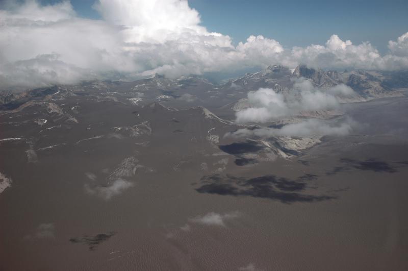 View to the northeast over Double Glacier	showing the extent of the cumulative tephra deposit that blankets the area immediately north of Redoubt Volcano.  Summer snowmelt has coalesced the several tephra layers into one that now covers the glaciers and snowfields.				