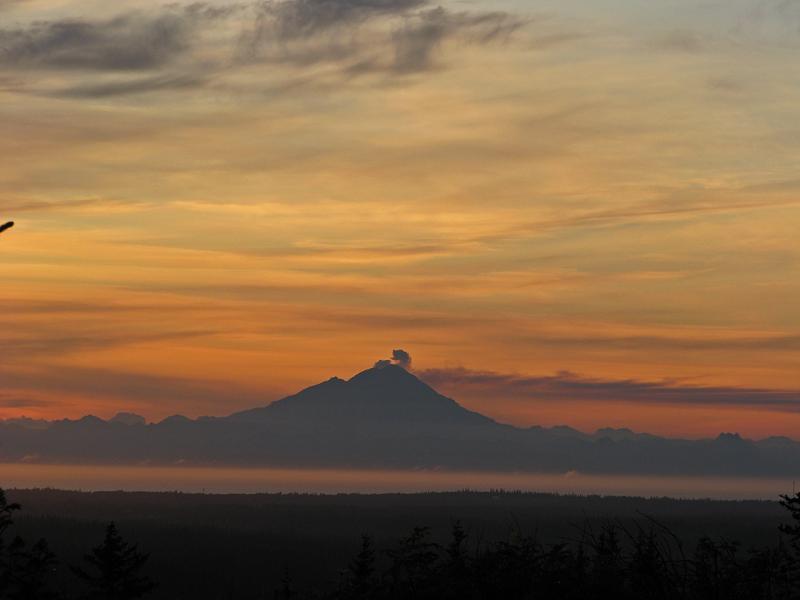 Redoubt's new dome steams gently, as seen from near Homer, AK, on the evening of July 14, 2009. Photograph courtesy of Dennis Anderson, Night Trax Photography.				