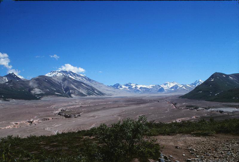 								View southeast up the Valley of Ten Thousand Smokes from the Overlook Cabin in Katmai National Park and Preserve, Alaska. The valley has been filled with up to 200 m
(660 ft) of ash-flow deposits from the 1912 eruption of Novarupta volcano. The rim of
Katmai Caldera is on the skyline at center-right.  Mount Griggs is the high, flat-topped, snow-covered peak left-center. Photograph by Game McGimsey, U.S. Geological
Survey, July 18, 1990.