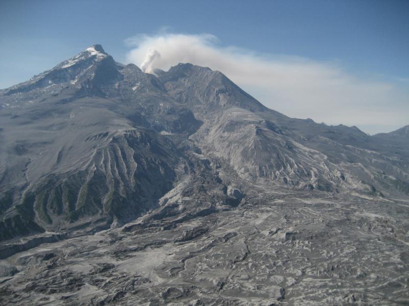 North side of Redoubt volcano, viewed from the NNE. In this image one can see a gas/steam plume rising from fumaroles around the new lava dome in the summit crater. The debris covered piedmont lobe of the Drift Glacier fans out at the base of the mountain. The upper Drift Glacier was eliminated during the eruption sequence, and the lower glacier badly scoured and eroded by lahars.  **AVO research technician Max Kaufman took these images during 3 days of campaign GPS work on and around Redoubt volcano: June 6,8,10 2009.