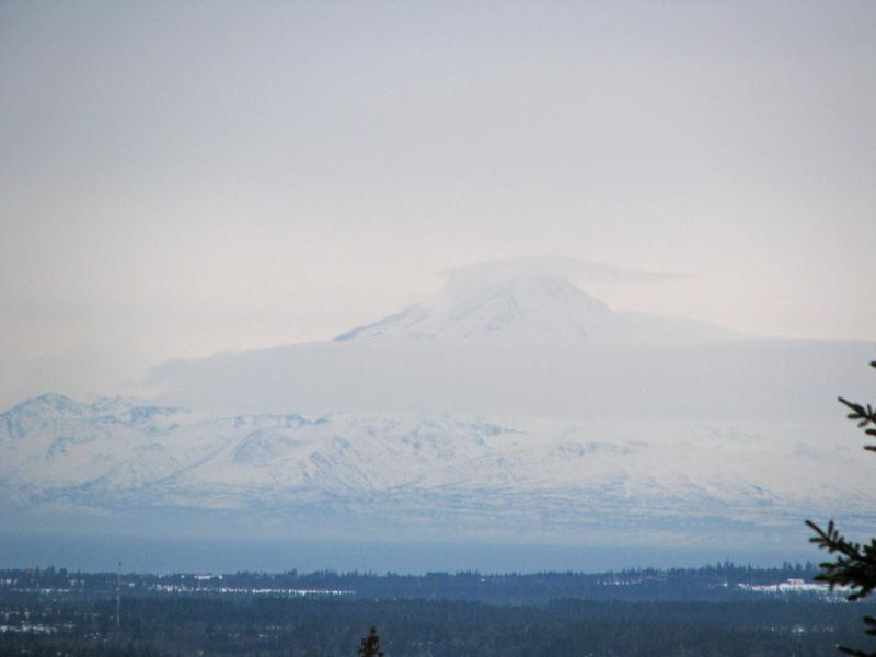 View of steaming and snow-covered Redoubt volcano on December 28, 2009, at 2:02 pm, as seen from Diamond Ridge, near Homer, AK. Photograph courtesy of Dennis Anderson, Night Trax Photography.			
