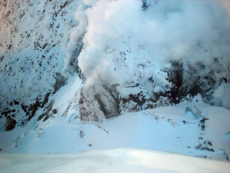 Photos of Redoubt Volcano and the 2009 lava dome taken during aerial inspection and gas measurement flight on December 31, 2009.

This is a look down onto the west margin of the steaming 2009 lava dome (upper right).  Note prominent fumaroles along the base of the dome. Even from a distance, bright yellow sulfur precipitate was visible around the base of the most vigorous fumaroles.  