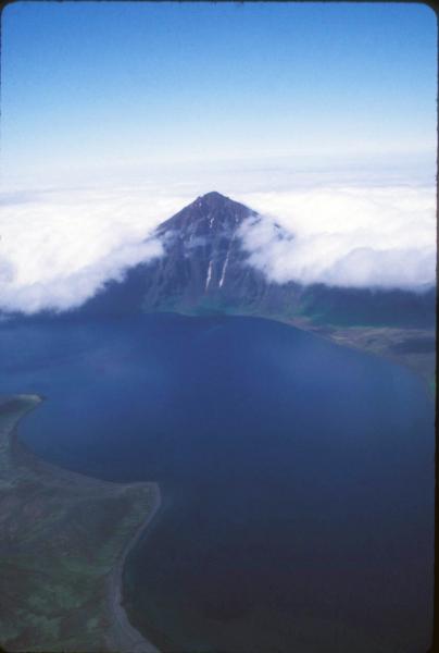 Eickelberg Peak being surrounded by incoming fog.  Eickelberg Peak is one of several pre-caldera stratovolcanoes partially destroyed in the caldera-forming eruption 9,400 years ago.  The western caldera lake is in the foreground; view to NW.