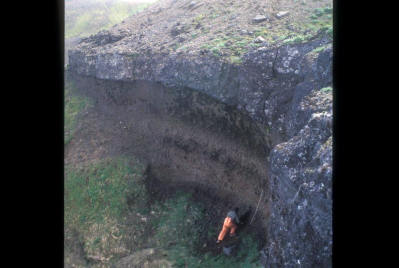 Deposits from the caldera-forming eruption 9,400 years ago, about 5 kilometers outside the eastern caldera wall.  AVO scientist Dr. Jim Gardner stand at the base of ~6.5 meters of pumice fall, capped by ~2.5 m of densely welded pyroclastic flow material.  Additional pyroclastic flow material above is obscured by slope wash.