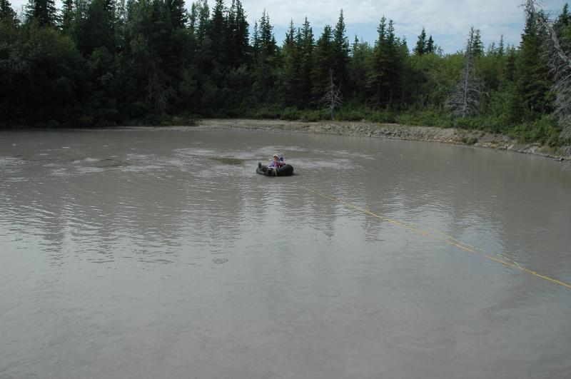 Sarah Henton preparing to sample the "black ooze" floating on the surface of Upper Klawasi mud volcano, seen here just to the left of the central upwelling and just beyond Sarah on the tire tube.