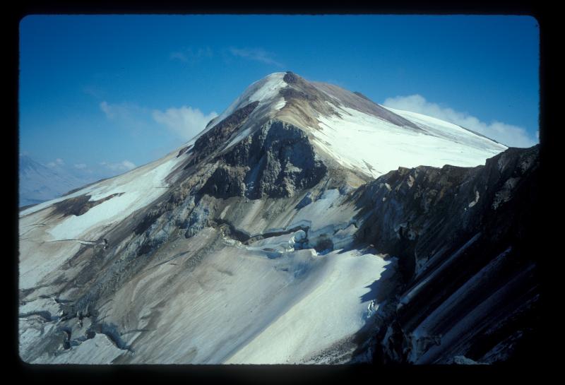 Aerial view of Alagogshak volcano, looking east-northeast at its glacially gutted crater. Alagogshak, located along the volcanic front about 15 km southwest of Katmai Pass, is a stratovolcano that produced 10-18 km3 of andesite and dacite eruptive products during the middle and late Pleistocene. Photo taken from sample site K-2262. 	