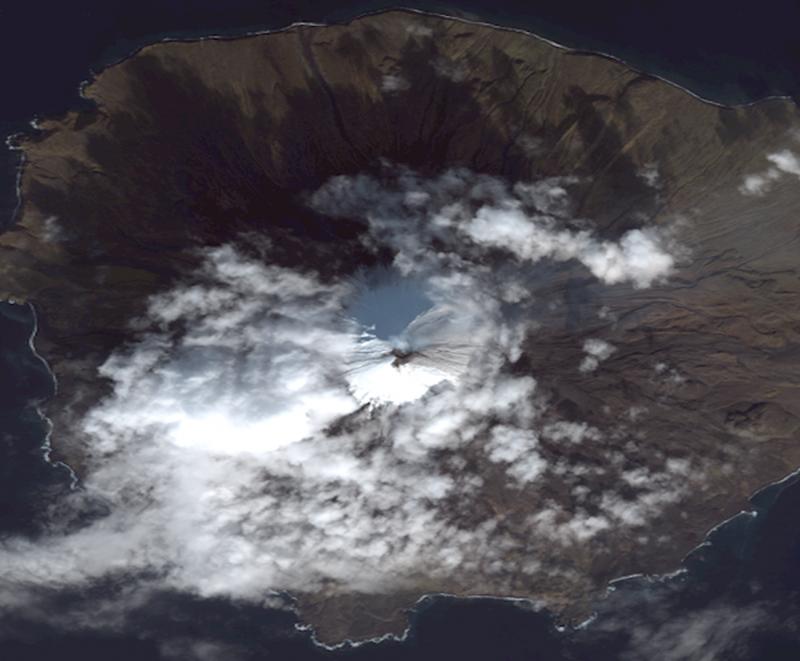 True-color satellite image of Cleveland Volcano collected by the Quickbird-2 sensor on October 15, 2011. The summit of the volcano is mostly snow-covered, and the growing lava dome is seen as the dark feature in the center of the image. Some snow-free ground is observed on the southern upper flanks of the volcano, just south (below) the of the crater. A faint steam and gas plume is observed moving towards the east (right). 