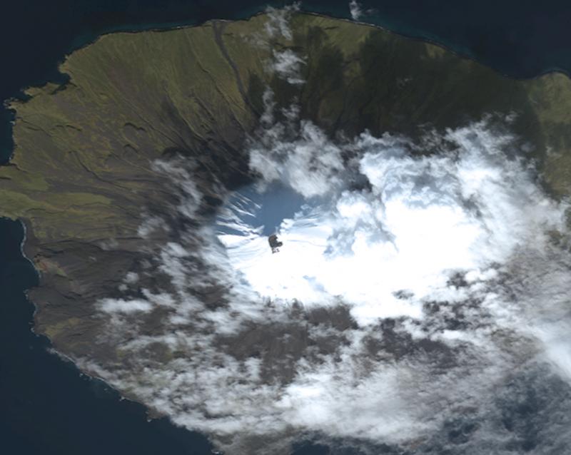 True-color satellite image of Cleveland Volcano collected by the Worldview-2 sensor on October 7, 2011. The summit of the volcano is mostly snow-covered, and the growing lava dome is seen as the dark feature in the center of the image. Some snow-free ground is observed on the southern upper flanks of the volcano, just south (below) the of the crater. A faint steam and gas plume is observed moving towards the northeast (upper-right). 