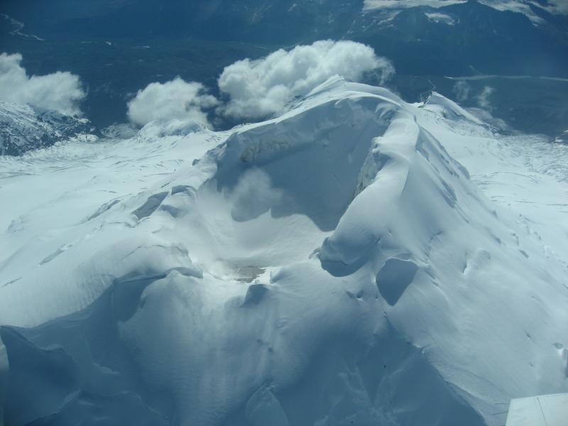 Aerial view from N into summit crater of Mount Spurr volcano.  Snow is slowly accumulating against the southern wall and the fumarole field remains active and snow-free.  