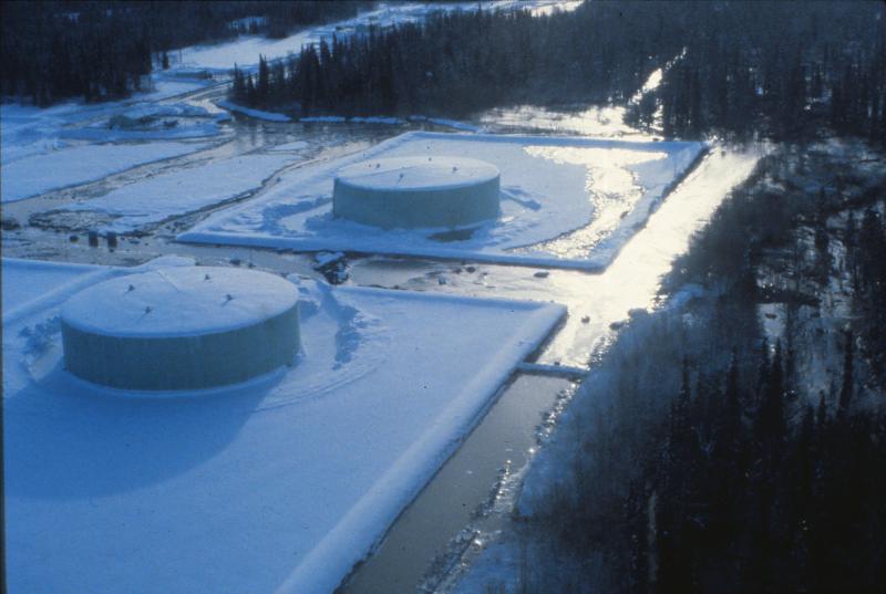 The February 15, 1990 eruption of Redoubt Volcano 
produced a lahar that overtopped the containment berm at 
the Drift River Oil Terminal but did not damage the storage 
tanks. Photograph by T. Miller, U.S. Geological Survey, 
February 15, 1990.