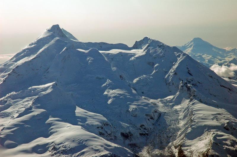 Aerial view from the north of Redoubt Volcano.  The ice-filled summit crater is breached to the north and feeds Drift Glacier down the north flank.  The 1990 dome is covered by crater ice, but recent thermal activity has melted several holes, exposing dome rock.  Warm melt water flowing beneath the Drift Glacier has opened a skylight hole at the top of a waterfall located at the prominent break in slope.