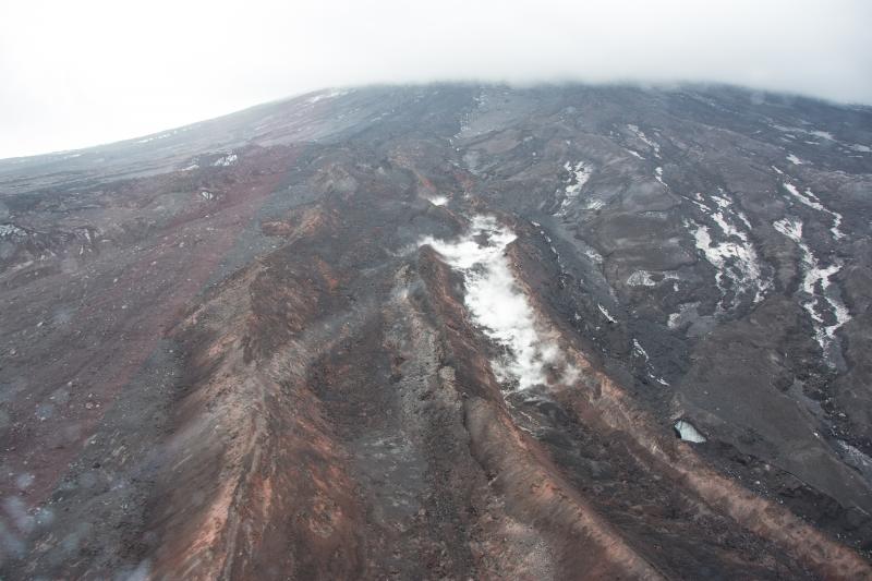 Recently emplaced lava flows on the north-northwest flank of Pavlof Volcano. The flows in the foreground were probably emplaced in May 2013, and the flow in the left background probably developed in June 2013. Steaming area in flow on right is the result of water flow along the axis of the lava flow. View is toward the south-southeast.