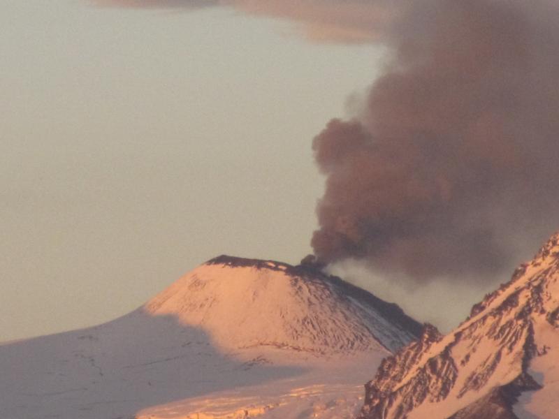 Telephoto view of erupting Veniaminof volcano on July 9, 2013. Photo taken from the Sandy River about 20 miles west of the volcano.  The summit of this cone is just over 7000 feet high.  On the far side of the cone, not visible in this view, lava was pouring down onto glacial ice.  