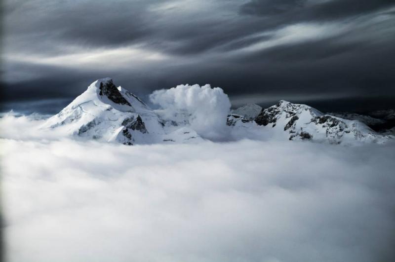 Redoubt Volcano within cloud layers as seen from an aircraft.  A vapor plume rises off the 2009 lava dome (hidden in clouds) and drifts downwind.  The summit of the volcano is 10,197 feet above sea level.
